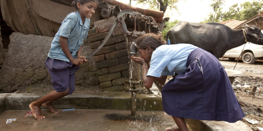 Girls pump water from a well