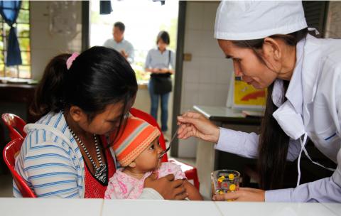 Infant girl receives oral rehydration solution (ORS) at a clinic in Cambodia.
