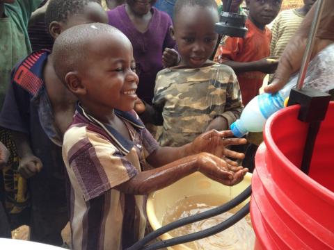 A young boy washes his hands at a handwashing station.