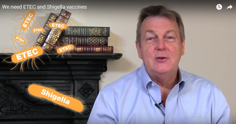 A man in a blue shirt sits next to a fireplace with books on it. Text "ETEC" and "Shigella" appear visually, emphasizing the topic of the need for ETEC and Shigella vaccines.