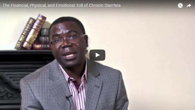 A man wearing glasses and a gray plaid suit jacket is speaking in front of a neutral background with a few books on a shelf behind him. The video title at the top reads, "The Financial, Physical, and Emotional Toll of Chronic Diarrhea." A play button symbol is displayed in the center.