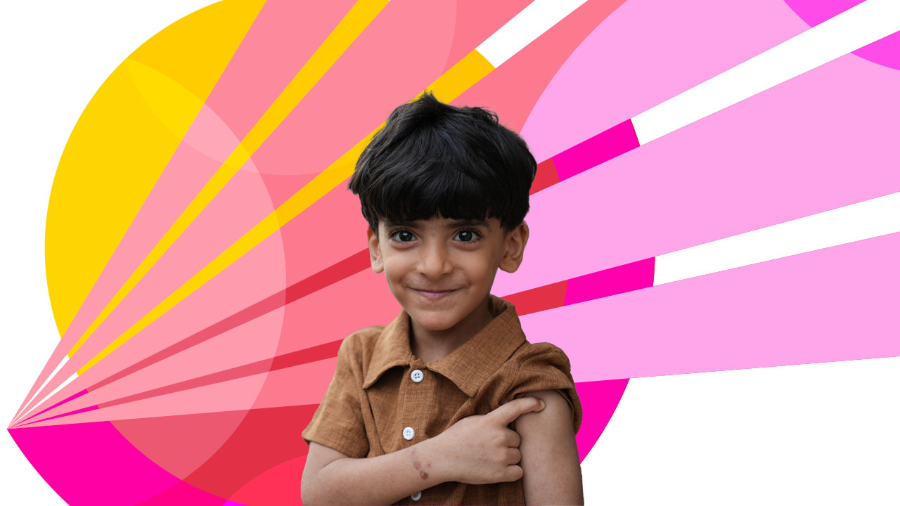 A young boy with dark hair wearing a brown shirt smiles at the camera. The background features a colorful, abstract design with overlapping shapes in shades of pink, red, and yellow. The boy has his arm slightly raised, touching his shoulder.