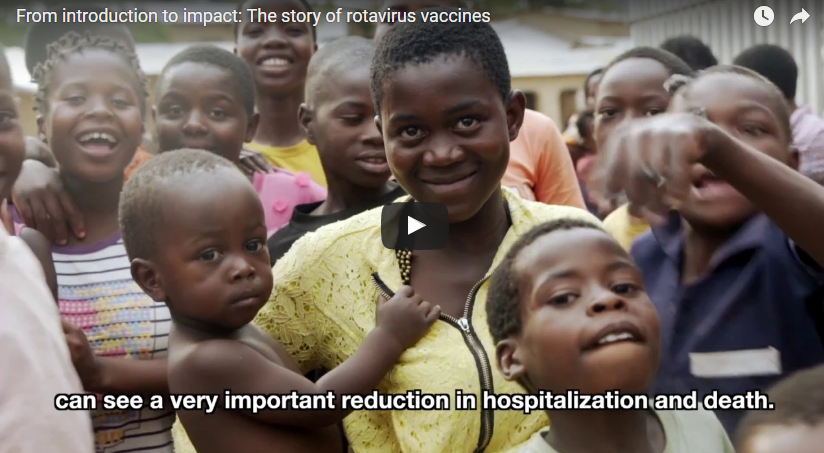 A group of children and a few adults are gathered together outdoors, smiling and looking at the camera. One woman is holding a young child. There's text at the bottom that reads "can see a very important reduction in hospitalization and death.