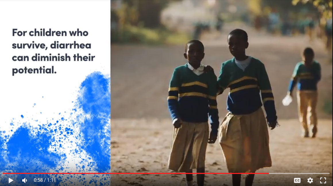 Two children in school uniforms are walking closely together on a dirt road. Nearby, text highlights the impact of diarrhea on children’s potential. The background is blurred, with more children visible in the distance.