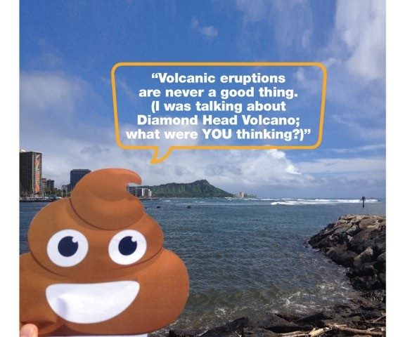 A paper cutout of a smiling poop emoji is held up against a backdrop of a coastal city and a mountain. The emoji has a speech bubble that says, "Volcanic eruptions are never a good thing. (I was talking about Diamond Head Volcano; what were YOU thinking?).