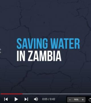 A paused video screen shows the text "Saving Water in Zambia" in large blue and white letters. The video progress bar at the bottom indicates the timestamp as 00:05 of a 00:42 long video. The background is a dark map with faint outlines.