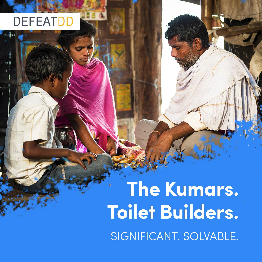 A man and two children sitting together inside a rustic setting. The man wears a white shirt with a scarf, and the girl is in a pink shawl. They seem engaged in discussion or learning. Text overlay reads: "The Kumars. Toilet Builders. Significant. Solvable.